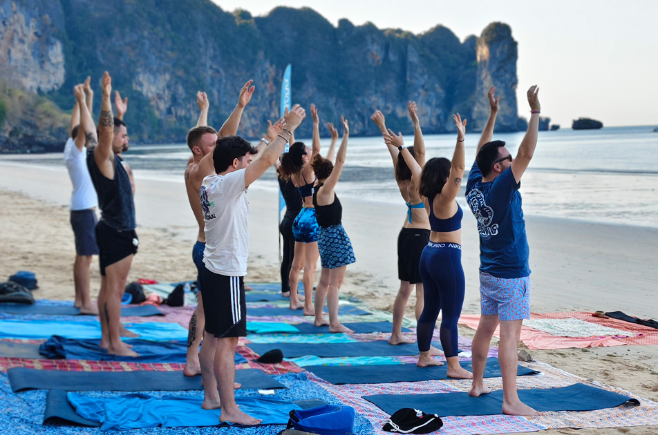 group of men and women doing a morning beach yoga session on aonang beach with samadee yoga